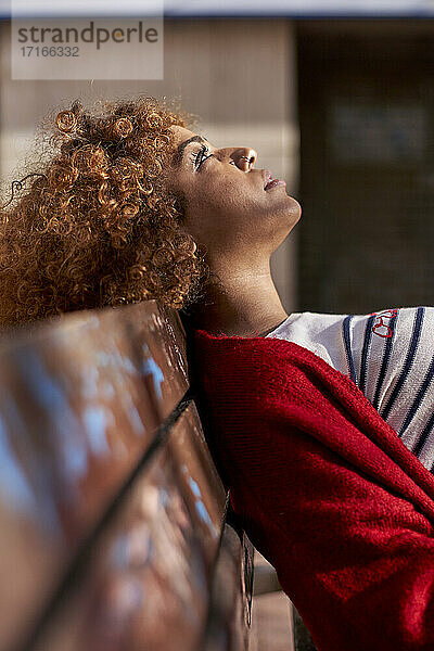 Thoughtful woman looking up while resting on bench