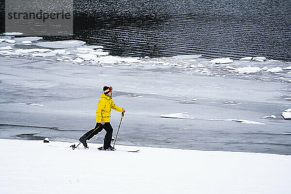 Man skiing by lake during winter