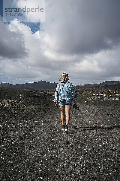 Tourist mit Kamera in der Hand auf dem Fußweg am Vulkan El Cuervo  Lanzarote  Spanien
