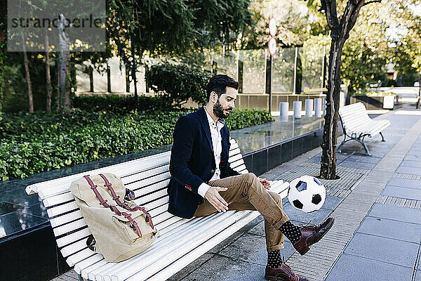 Businessman playing with ball while sitting on bench