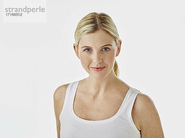 Smiling woman staring while standing against white background