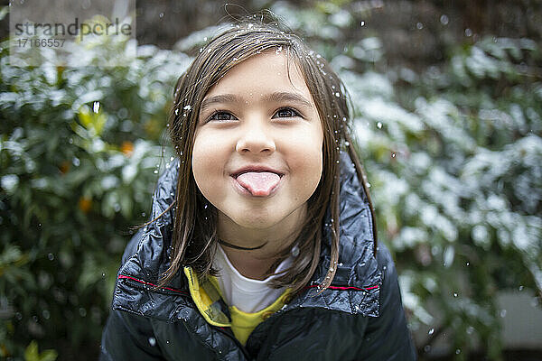Cute girl sticking out tongue during snowfall