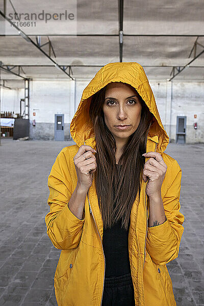 Beautiful female dancer in yellow jacket at abandoned factory