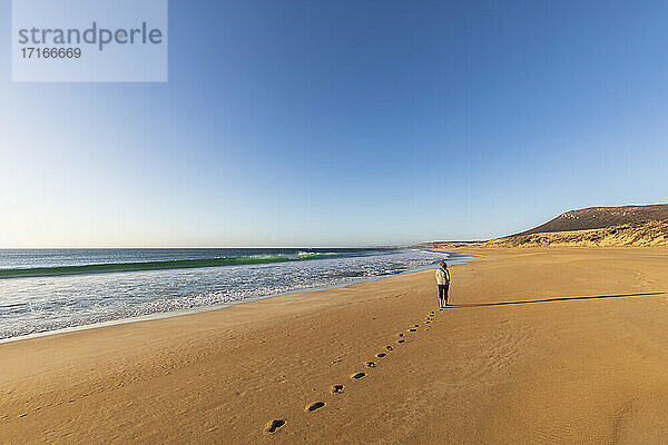 Klarer Himmel über einer Frau  die allein am Greenly Beach spazieren geht