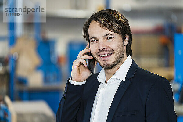 Entrepreneur talking on mobile phone while standing at industry