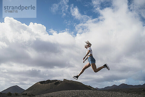 Junge Frau läuft gegen den Himmel am Vulkan El Cuervo  Lanzarote  Spanien