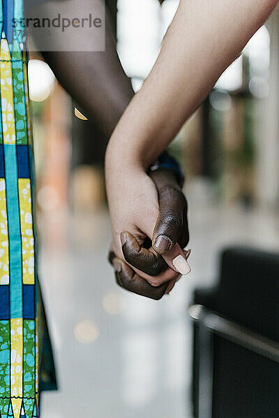 Young man and woman holding hands while standing outdoors