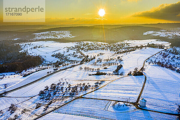 Drohnenansicht von schneebedeckten Feldern bei Wintersonnenuntergang