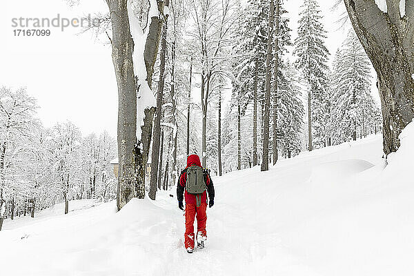 Mann geht im tiefen Neuschnee im Wald