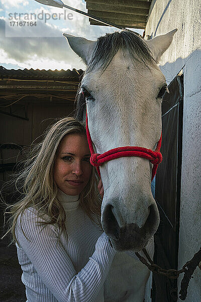 Woman embracing horse while standing at stable