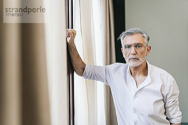 Mature man standing by window in hotel room