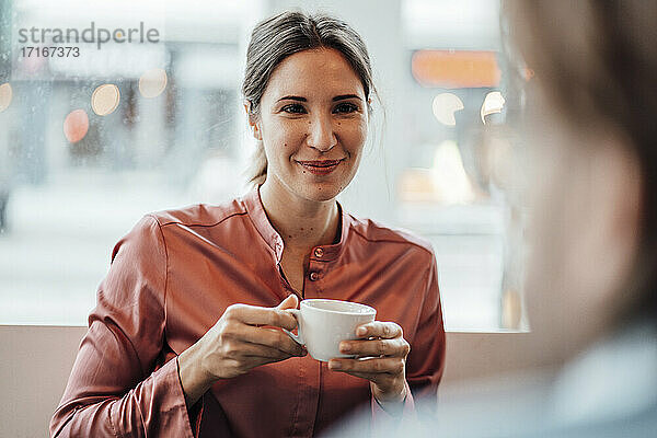 Eine Frau trinkt Kaffee und diskutiert mit einem männlichen Kollegen in einem Café