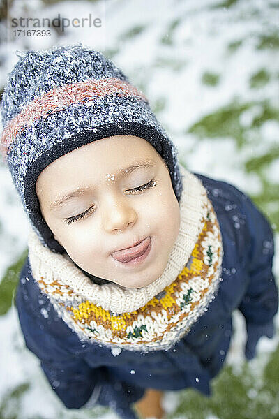 Cute girl with eyes closed sticking out tongue during winter