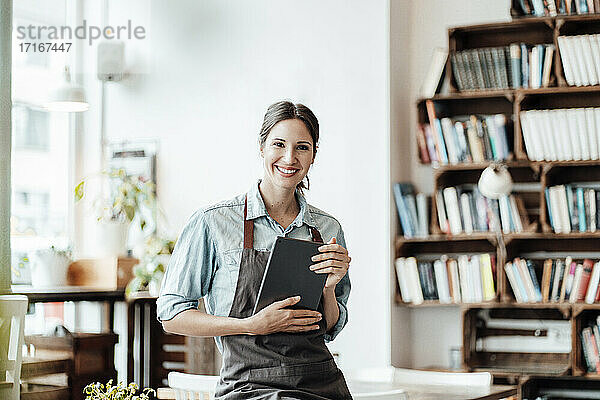 Lächelnde Café-Besitzerin mit digitalem Tablet in einem Coffeeshop