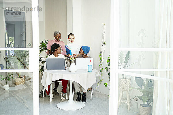 Female colleagues discussing seen through doorway at home