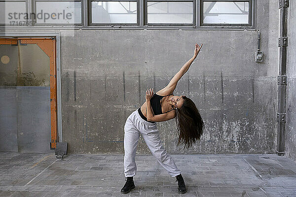 Female dancer practicing against wall in abandoned factory