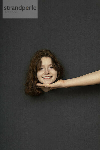 Studio shot of head of teenage girl touched by male hand