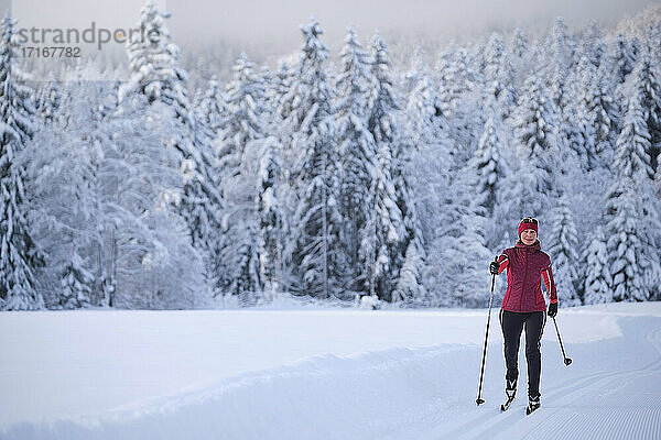 Frau in Warnkleidung beim Skifahren mit Skistock im Schnee