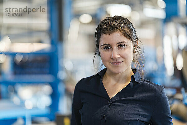 Young businesswoman staring while standing at industry