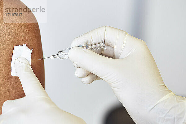 Hände eines Arztes  der einem Patienten im Krankenhaus einen Impfstoff injiziert