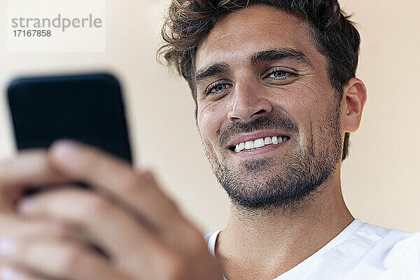 Mann lächelnd bei der Benutzung eines Mobiltelefons zu Hause