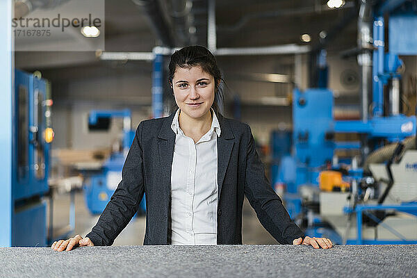 Young businesswoman smiling while standing at industry