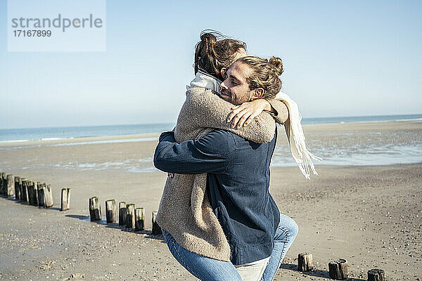 Freund umarmt Freundin beim Abholen am Strand während des Wochenendes
