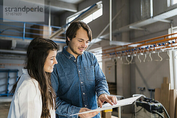 Smiling expertise pointing on file while working with colleague in industry