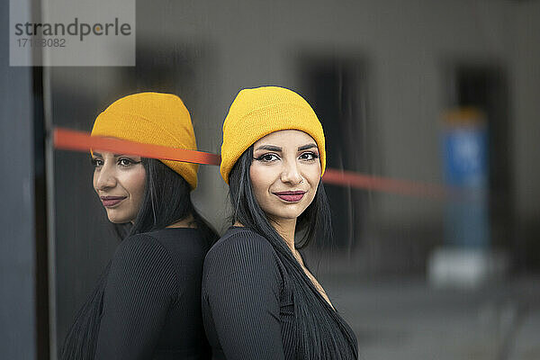 Beautiful young woman with yellow knit hat against glass