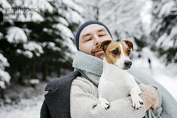 Mann betrachtet Jack Russell Terrier Hund im Winter