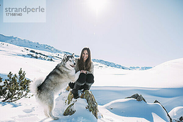 Young woman with her dog in snow covered land against clear sky