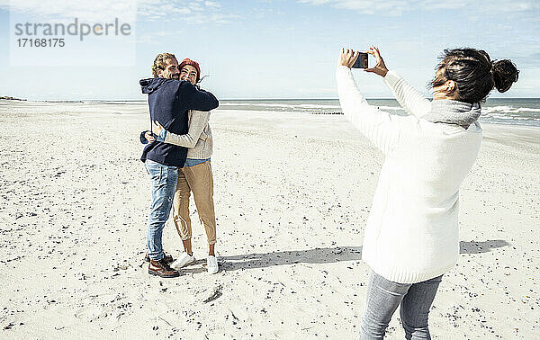 Eine Gruppe von Freunden macht Smartphone-Fotos am Sandstrand