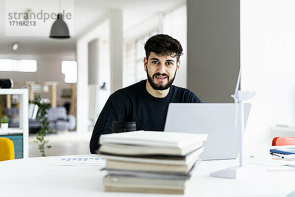 Porträt eines jungen Geschäftsmannes mit Laptop in einem kreativen Büro