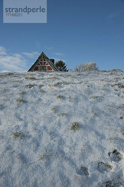 House roof peeking out from behind snow-covered levee