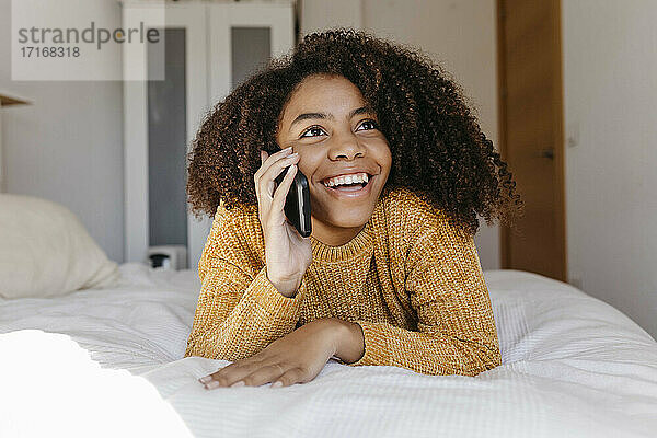 Lächelnde Frau  die mit ihrem Handy telefoniert  während sie sich zu Hause ausruht