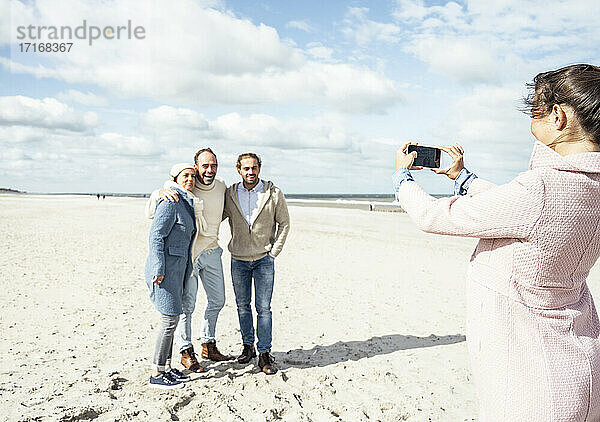 Eine Gruppe von Freunden macht Smartphone-Fotos am Strand