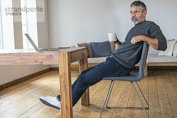 Geschäftsmann trinkt Kaffee  während er im Büro zu Hause sitzt