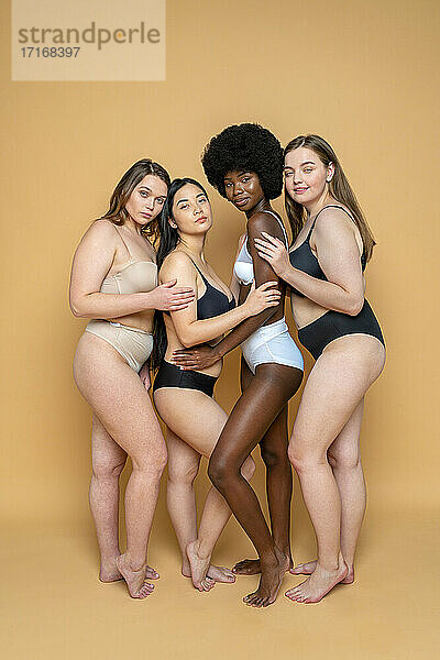 Gruppe multiethnischer weiblicher Modelle in Dessous vor gelbem Hintergrund