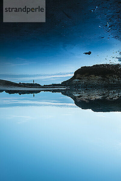 Silhouette einer Frau  die sich in einem blauen See in der Abenddämmerung spiegelt  Asturien  Spanien
