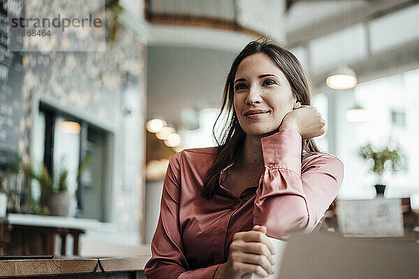 Lächelnde Geschäftsfrau  die in einem Café sitzt und nachdenkt