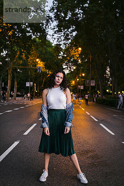 Schöne Frau in Jeansjacke posiert auf der Straße im Park in der Abenddämmerung