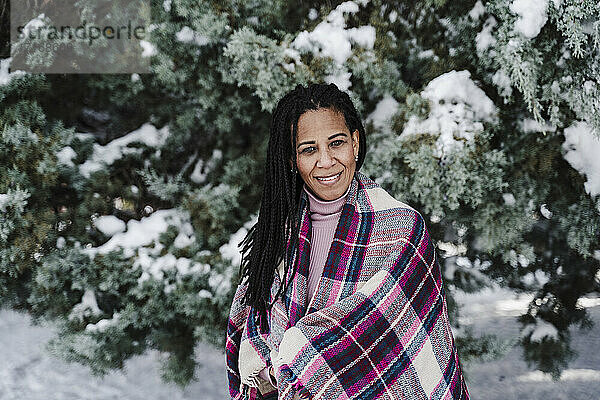 In einen Schal gehüllte hispanische Frau im Winter im Park