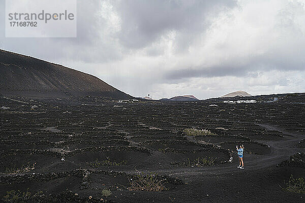 Weibliche Touristin erkundet Weinberg am Vulkan El Cuervo  Lanzarote  Spanien