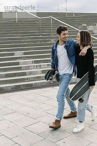 Junges Paar mit Skateboards geht in der Nähe von Stufen