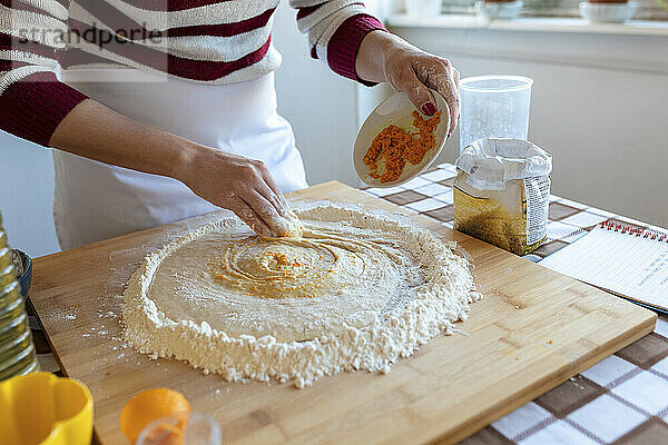 Woman mixing ingredient in dough while preparing criossants at home