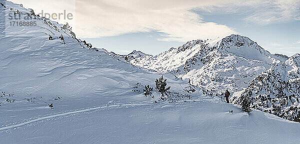 Mature male skier at ski slope of Pyrenees against cloudy sky