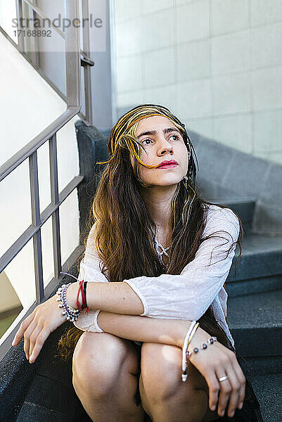 Hippie nachdenkliche junge Frau mit langen Haaren sitzt auf Stufen