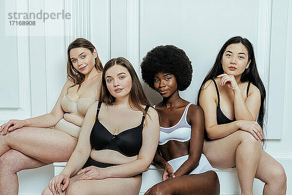 Schöne multi-ethnische Gruppe von Mode-Modelle in Dessous gegen weiße Wand