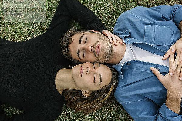 Lächelndes Paar auf dem Rasen liegend mit geschlossenen Augen