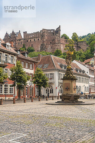 Germany  Baden-Wurttemberg  Heidelberg  Muttergottesbrunnen fountain on empty Kornmarkt square with Heidelberg Castle in background
